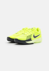 Klare gule joggesko med svarte detaljer, mesh-overdel og teksturert såle. Har lisser og en fremtredende Nike-logo på siden.