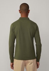 Polo majica dugih rukava u maslinasto zelenoj pamuku. Ima klasični ovratnik i rukave s manžetama. Glatka tekstura i prilagođen kroj.