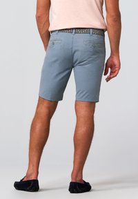 Light blue shorts made of soft fabric, with a fitted design, flat pockets, and a patterned belt. Worn with navy blue slip-on shoes.