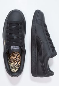 Baskets en cuir noir avec lacets noirs, semelle en caoutchouc texturée, col rembourré et semelle intérieure dorée à motif présentant le logo Puma.