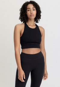 Black athletic crop top with a rounded neckline and a fitted design, paired with high-waisted black leggings, both made of smooth fabric.