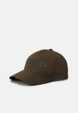 Casquette de baseball marron avec visière incurvée et inscription "HUGO" en relief noir sur le devant, présentée sur fond blanc.