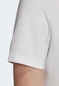 Korte mouwen witte katoenen t-shirt met een gladde textuur, ronde halslijn en dubbele stiknaaddetail op de mouw.