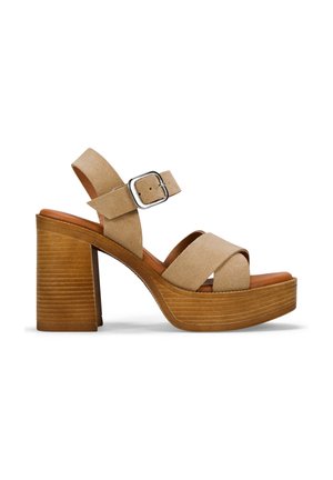 Sandalias de plataforma de ante beige con un diseño de tira cruzada ancha, correa de tobillo ajustable y un tacón bloque texturizado similar a la madera.