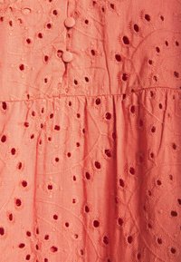 Robe en coton corail ornée de broderies florales élaborées, de boutons ronds et d'une jupe évasée avec une finition texturée.