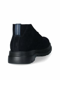 Stivali ankle in suede nera con punta arrotondata, suola in gomma testurizzata a contrasto e un'etichetta blu con il nome del brand sul retro.
