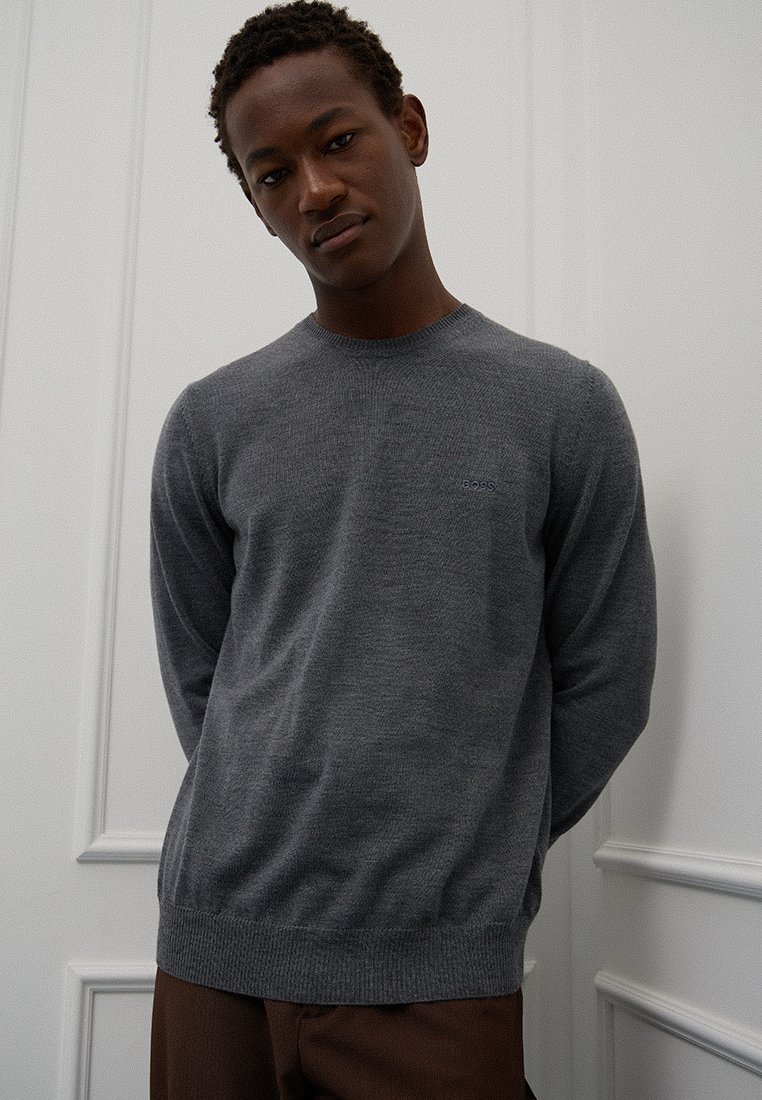 Maglione grigio a maglia con collo rotondo, polsini e orlo a costine. Presenta un logo discreto sul petto, realizzato in un morbido tessuto misto lana.