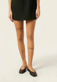 Genomskinliga, bruna strumpbyxor har tre tryckta fraser i svart kursiv stil: "Allt sker av en anledning," "le varje dag," och "Gör idag fantastisk."