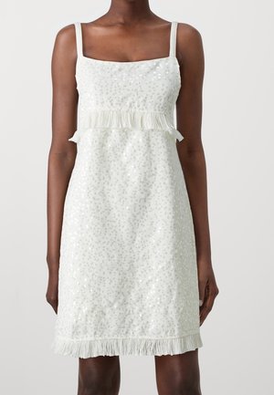 Biała sukienka z kwadratowym dekoltem, cienkimi ramiączkami i frędzlami na dole. Całość pokryta małymi, refleksyjnymi cekinami, które nadają teksturę.