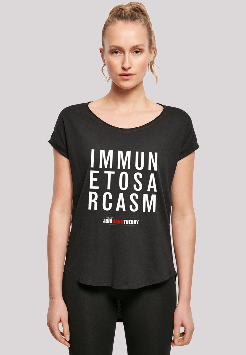 Svart T-skjorte med korte ermer laget av mykt stoff, med fet hvit tekst "IMMUN ETOS ARCASM" og "#BIGBANGTHEORY" i rødt. Rund halsutskjæring og avslappet passform.