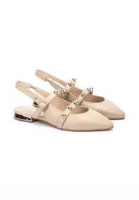 Scarpe slingback in pelle beige con punta appuntita, dotate di borchie dorate sui cinturini frontali e un accento di tacco metallico lucido.