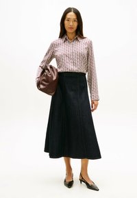 Blusa de manga larga con estampado en tonos rosa y blanco combinada con una falda A-line de mezclilla oscura y tacones slingback de punta negra.