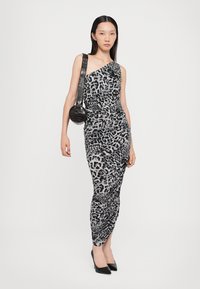 Rochie cu un umăr, cu imprimeu leopard în nuanțe de gri, design drapat cu plissare, asortată cu o geantă circulară neagră și tocuri negre.