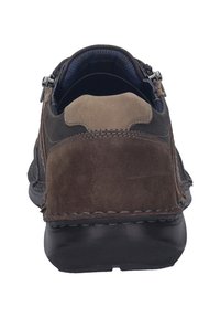 Chaussures en cuir suédé marron avec un col rembourré, semelle en caoutchouc noire et fermeture éclair métallique sur le côté. Détails de couture visibles.