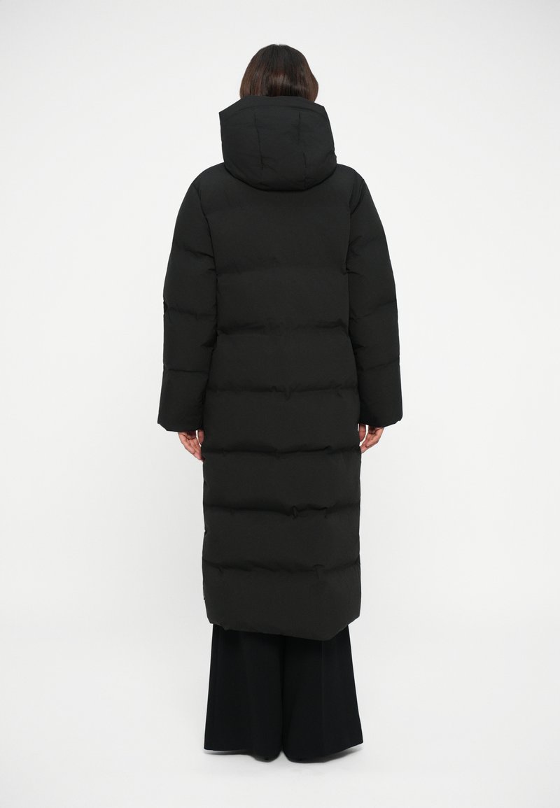 Black puffer coat with a hood, featuring a long, rectangular shape, quilted texture, and elastic cuffs, extending down to mid-calf.