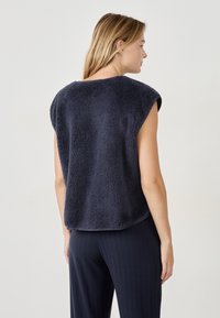 Granatowy bezrękawnik z polaru o miękkiej, textured powierzchni i luźnym kroju, z okrągłym dekoltem i zaokrąglonym hem.