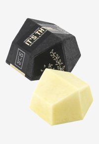 Herbal body butter in a yellow, geometric solid with a textured surface, packaged in a matte black box with gold accents and botanical design.
