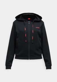 Svart zip-up hoodie i mjukt tyg, med huva, framfickor och röd "HUGO" logga på bröstet och dragsko.
