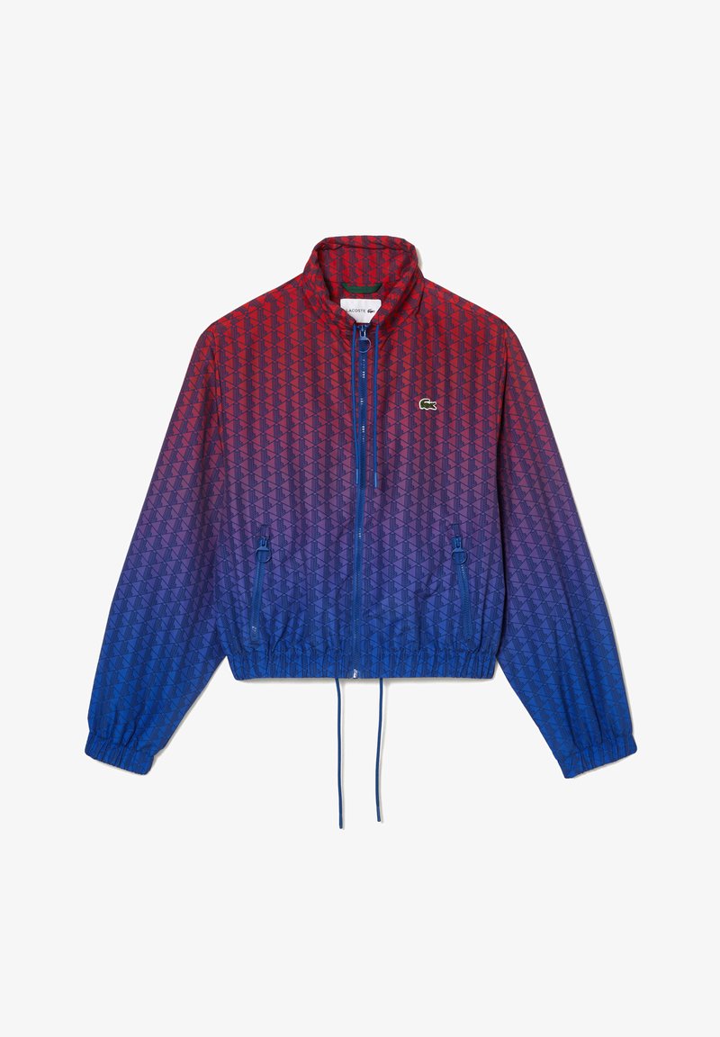Červeno-modrá gradientová větrovka s geometrickým vzorem, se zipovým uzávěrem, stojáčkem, elastickými manžetami a stahovacími lemy. Logo Lacoste.