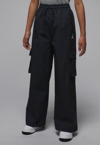 Pantaloni cargo neri con vita con coulisse, tasca frontale con zip e tasche laterali. Logo in evidenza sul lato destro; il tessuto è liscio e leggero.