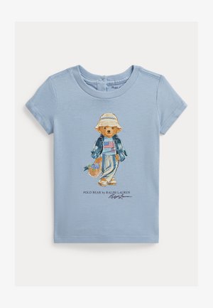 Svijetloplava majica kratkih rukava s izvezenim crtanim medvjedom u slamnom šeširu, traper jaknom, prugastom majicom i koji nosi košaru s cvijećem.