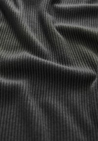 Tissu en ribbed gris avec une texture douce, présentant des lignes verticales régulièrement espacées. Le matériau semble léger et flexible.