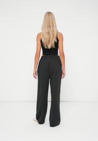 Top court noir associé à un pantalon noir ample. L'ensemble présente un design décontracté, avec une taille élastique et des jambes évasées.