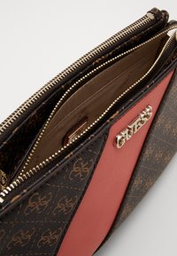 Brun og lyserød taske med guldfarvede detaljer, lynlåslukning og indvendige lommer. Fremstillet af mønstret syntetisk materiale og glatte læderdetaljer.