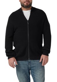 Zwarte ribgebreide zip-up trui met een hoge kraag, voorzien van lange mouwen, een gladde textuur en een minimalistisch ontwerp. Gekozen over een wit T-shirt.