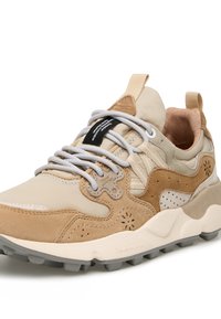 Scarpe sportive beige realizzate con materiali in suede e tessuto, colletto imbottito, suola in gomma grigia e cuciture a contrasto. Presentano lacci piatti e un'etichetta con il marchio.