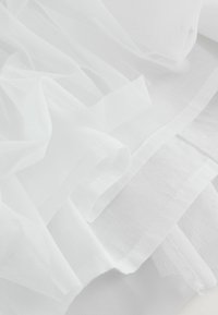 Valge tüllkangas pehme, õhulise tekstuuri ja kerge kaaluga, kihtide kaupa sujuva puuvillaga. Omab lainelist, õrnat langevust.