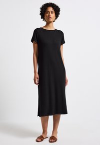Černé žebrované midi šaty s krátkými rukávy a kulatým výstřihem. Disponují rovný střihem a postranními štěrbinkami pro pohodlný pohyb.