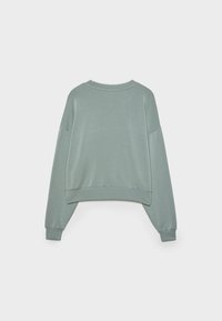 Sudadera corta de color verde claro con escote redondo, hombros caídos y puños acanalados. Tela suave con una textura lisa.