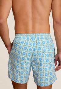 Blauwe en gele geblokte zwembroek met een elastische tailleband, voorzien van een geometrisch tegelpatroon en een losse pasvorm.