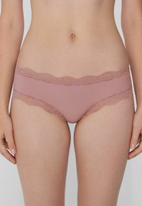 Světlé růžové spodní prádlo s krajkovým lemem, vyrobené z hladké látky, s vlnitými okraji a nízkým pasem, navržené pro pohodlí a skvělé padnutí.