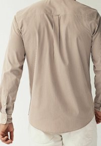 Gestreiftes Hemd mit Knopfleiste in Beige und Creme, mit geradem Schnitt, langen Ärmeln und abgerundetem Saum mit einer Rückenfalte.