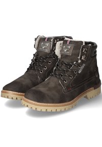 Botas de ante marrón con tobillo acolchado, costuras blancas y suela de goma texturizada. Presentan ojales de metal y etiquetas de marca.