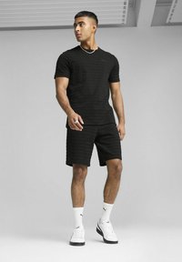Set de tricou cu dungi negre și pantaloni scurți, confecționat dintr-un material respirabil. Șosete albe și teniși completează ținuta. Accesoriile din argint sunt incluse.