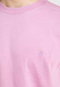 Rosa bomulls t-skjorte med rund hals og korte ermer, med en liten brodert logo på venstre bryst.