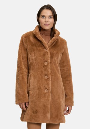 Manteau en fausse fourrure marron avec col châle, boutons devant, deux poches latérales et une surface douce et texturée. Design classique, longueur genou.