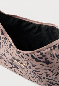 Ανοιχτό καφέ πουγκί με μαύρα αφηρημένα σημεία, χρυσό λογότυπο Puma στο μπροστινό μέρος και μαύρο ύφασμα εσωτερικά με τσεπάκι με φερμουάρ.