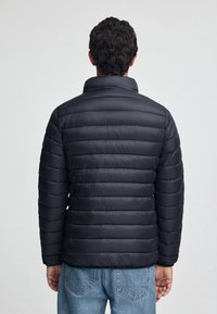 Czarna kurtka puchowa z poziomym pikowaniem, wysokim kołnierzem i długimi rękawami. Gładka tekstura i lekki wygląd.