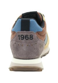 Sneaker in suede marrone e corduroy con tallone in materiale sintetico blu, texture morbida, design retrò e l'anno "1968" stampato sul retro.