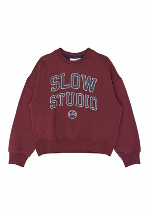 Bordowa bluza z okrągłym dekoltem, ściągaczami na mankietach i u dołu, z dużym białym i granatowym napisem "SLOW STUDIO" oraz małym logo w kształcie półkola poniżej.