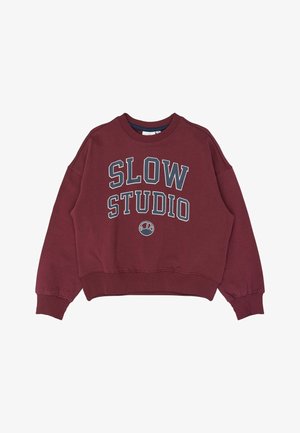 Mørkerød crewneck sweatshirt med ribkanter ved ærmer og bund, med stor hvid og marineblå tekst "SLOW STUDIO" og en lille halvmåneformet logo nedenunder.