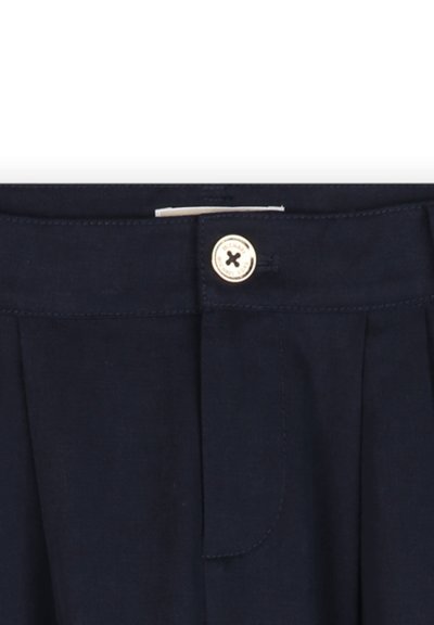 Marineblauwe broek met een geplooide voorkant, knoopsluiting en subtiele textuur. Voorzien van een goudkleurige knop met een kruispatroonaccent.