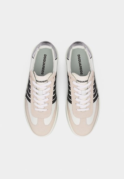 Paire de baskets blanches et beige avec des bandes noires, des lacets blancs et le logo DSQUARED2 sur la languette et la semelle intérieure, vues de dessus.