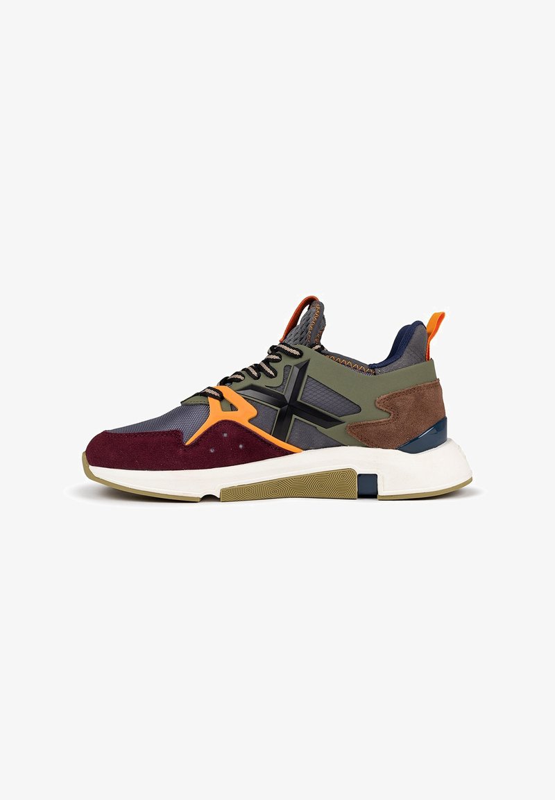 Zapatilla deportiva que presenta una combinación de gris, verde oliva, burdeos y acentos en naranja. Fabricada con malla, ante y goma, con una suela texturizada.