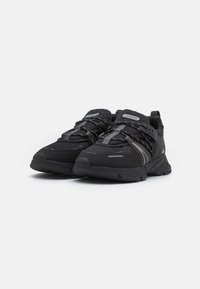 Black athletic shoes with textured mesh upper, reflective accents, and cushioned sole. Features lace-up design and branded details.