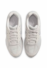 Vita atletiska skor med meshupp, snördesign, silverdetaljer och "Air Pegasus"-logotyp på tungan. Strukturad gummisula.